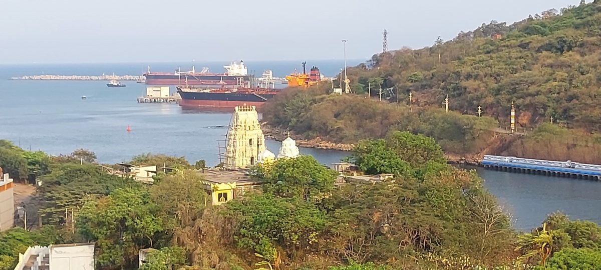 Oil tankers at an Indian port with hillside temple